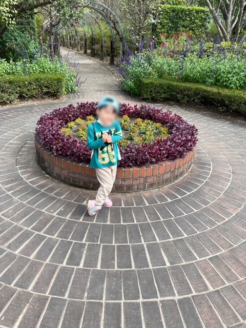 デンパーク内にある花壇の前でポーズをキメる娘の写真