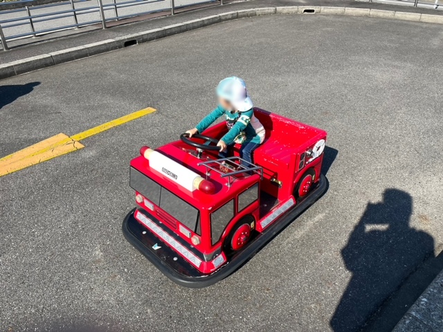 交通広場内の消防車のバッテリーカーを楽しむ娘の写真
